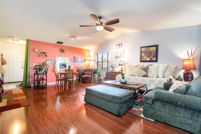 living room with vaulted ceiling, ceiling fan, hardwood / wood-style flooring, and a textured ceiling