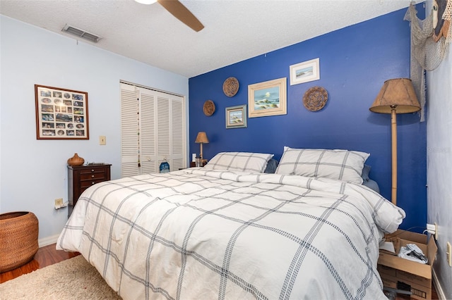 bedroom with a textured ceiling, wood-type flooring, ceiling fan, and a closet