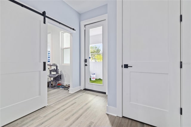 entryway with a barn door and light hardwood / wood-style flooring