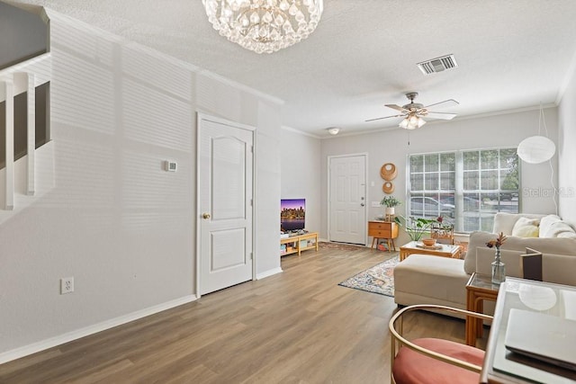 living room featuring ceiling fan with notable chandelier, ornamental molding, and hardwood / wood-style floors