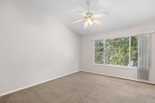 carpeted spare room featuring vaulted ceiling and ceiling fan