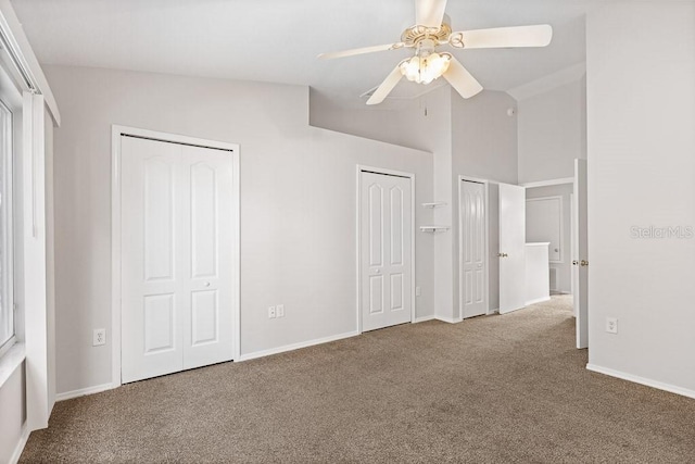 unfurnished bedroom with carpet flooring, vaulted ceiling, ceiling fan, and multiple closets