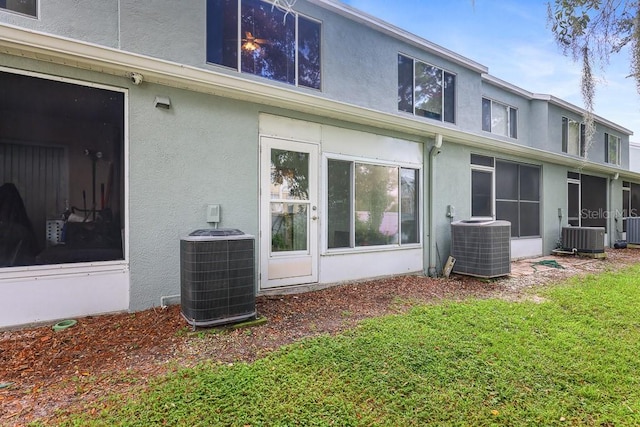 back of house with central AC unit, a sunroom, and a lawn