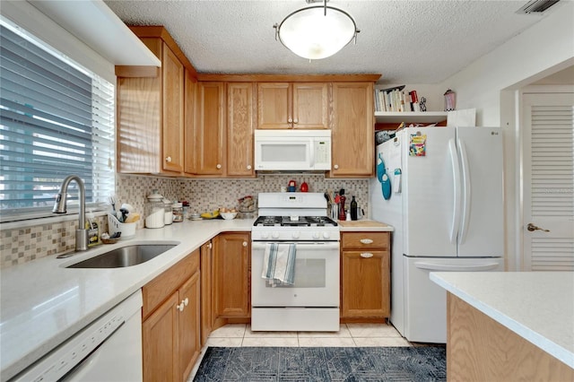 kitchen with backsplash, white appliances, light tile patterned floors, a textured ceiling, and sink