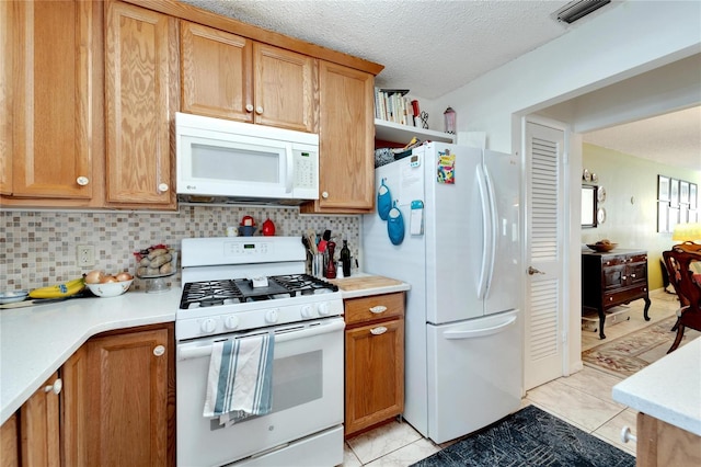 kitchen featuring white appliances, a textured ceiling, light tile patterned flooring, and backsplash