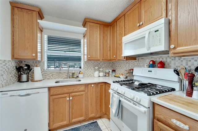 kitchen with light tile patterned flooring, sink, white appliances, a textured ceiling, and backsplash