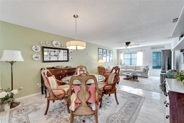 dining space with ceiling fan, light tile patterned floors, and a textured ceiling