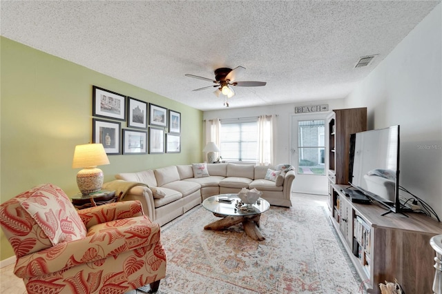 living room featuring ceiling fan and a textured ceiling