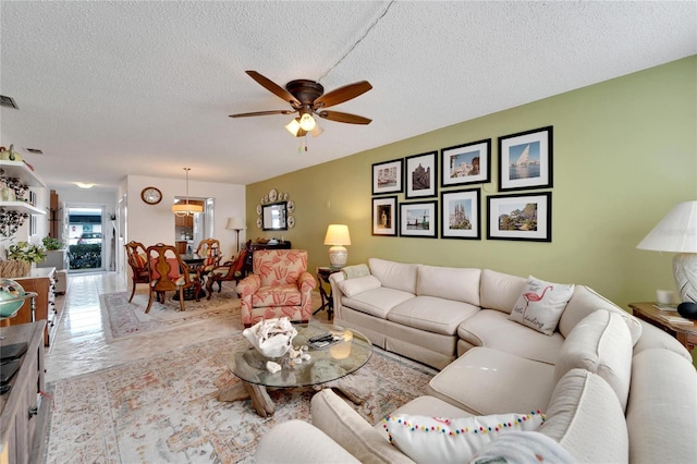 living room with ceiling fan and a textured ceiling