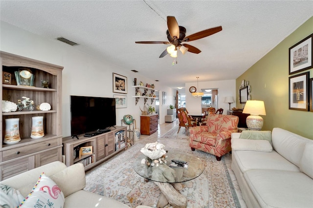 tiled living room featuring ceiling fan and a textured ceiling