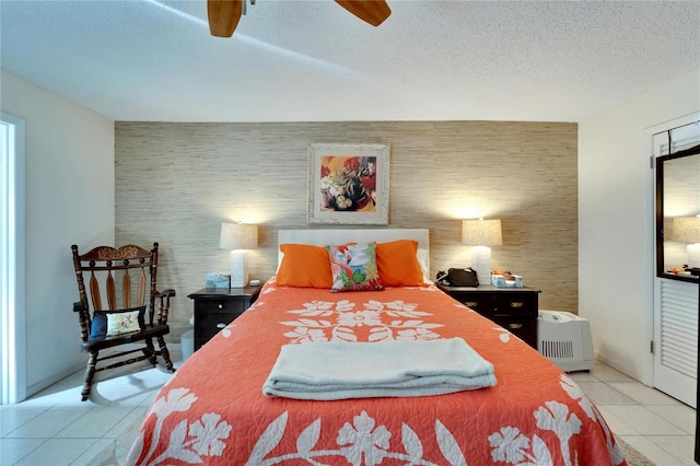 bedroom with a textured ceiling, light tile patterned flooring, and ceiling fan