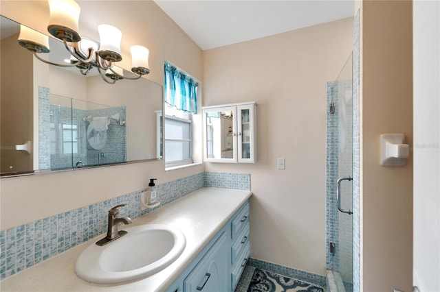 bathroom featuring a notable chandelier, vanity, and a shower with shower door