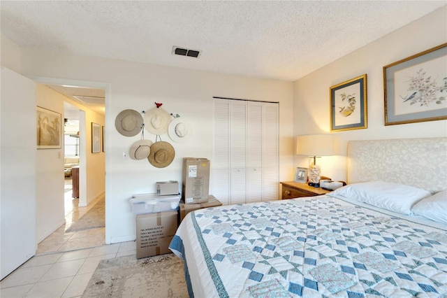 tiled bedroom with a closet and a textured ceiling