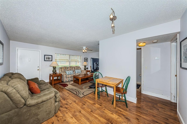 living room featuring dark wood-type flooring, a textured ceiling, and ceiling fan