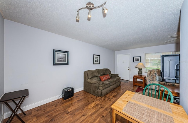 living room featuring dark wood-type flooring, ceiling fan, and a textured ceiling