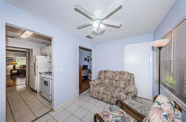 living room featuring a textured ceiling, light tile patterned flooring, and ceiling fan