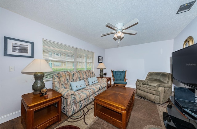 living room with ceiling fan and a textured ceiling