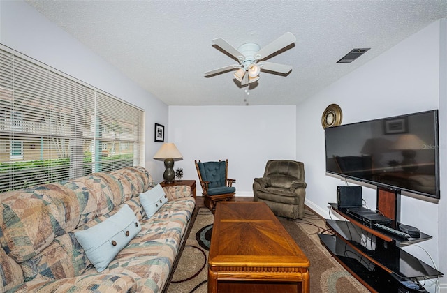 living room featuring a textured ceiling, carpet flooring, and ceiling fan