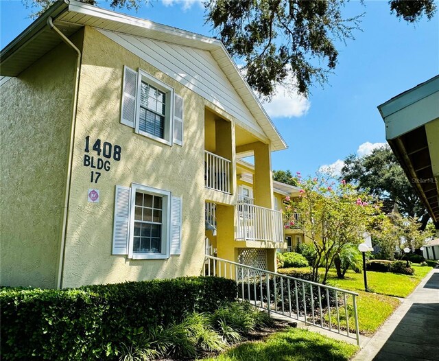 view of side of property featuring a balcony and a yard