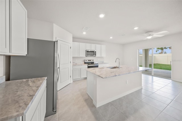 kitchen with stainless steel appliances, white cabinets, sink, an island with sink, and light tile patterned flooring