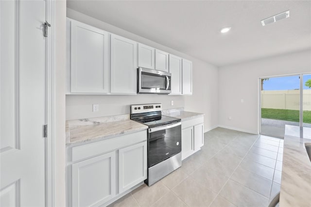 kitchen with light stone countertops, appliances with stainless steel finishes, light tile patterned flooring, and white cabinets