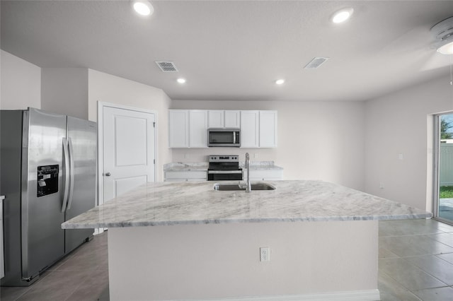 kitchen featuring a center island with sink, sink, light stone countertops, white cabinetry, and appliances with stainless steel finishes