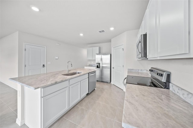 kitchen featuring a center island with sink, sink, white cabinetry, appliances with stainless steel finishes, and light stone countertops