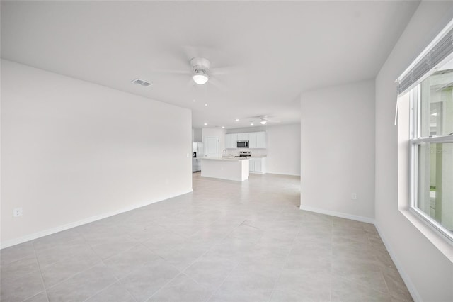 tiled empty room featuring a wealth of natural light and ceiling fan