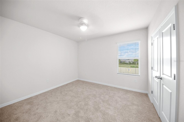 empty room featuring ceiling fan and light carpet