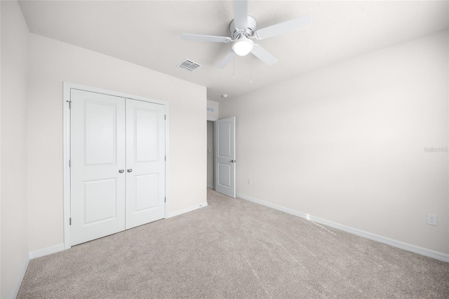 unfurnished bedroom featuring ceiling fan, light carpet, and a closet