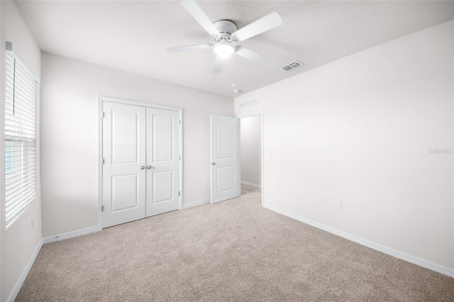 unfurnished bedroom with light colored carpet, ceiling fan, and a closet