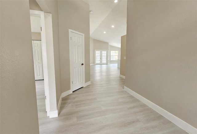 corridor with light hardwood / wood-style floors and vaulted ceiling