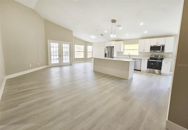 kitchen featuring pendant lighting, a center island, french doors, white cabinetry, and stainless steel appliances