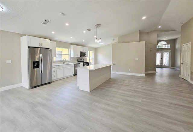 kitchen featuring stainless steel appliances, sink, white cabinets, a kitchen island, and hanging light fixtures