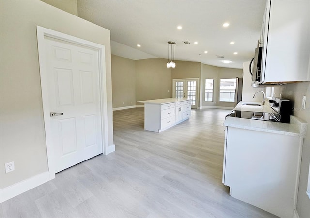 kitchen with pendant lighting, white cabinets, light hardwood / wood-style flooring, vaulted ceiling, and a kitchen island