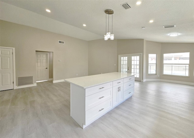 kitchen with white cabinets, a textured ceiling, decorative light fixtures, and lofted ceiling