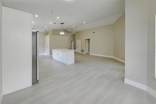 interior space featuring a kitchen island, light hardwood / wood-style flooring, decorative light fixtures, vaulted ceiling, and white cabinets