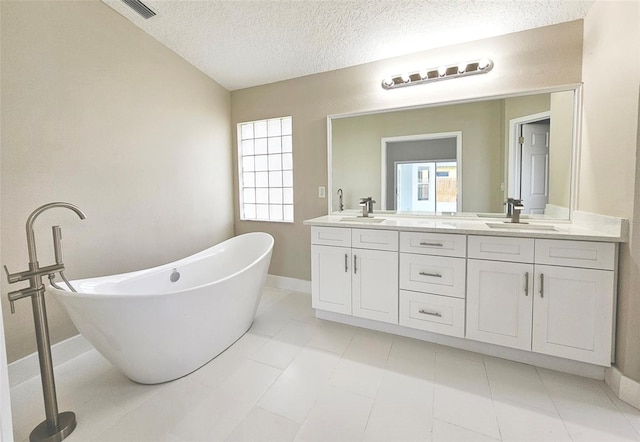 bathroom featuring a textured ceiling, vanity, and a bathtub