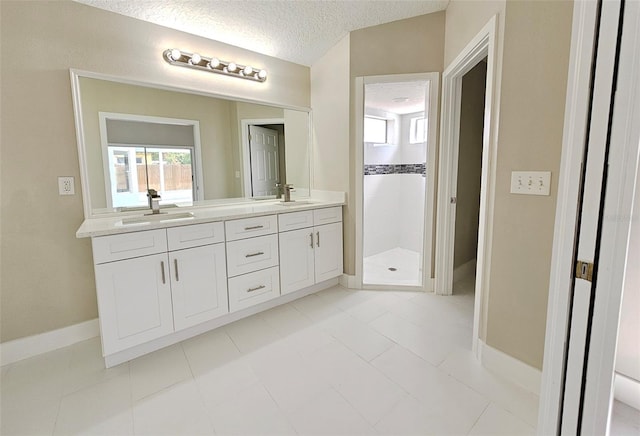 bathroom featuring tiled shower, vanity, a textured ceiling, and tile patterned flooring