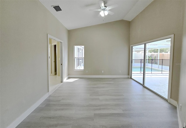 empty room featuring a wealth of natural light, ceiling fan, light hardwood / wood-style floors, and lofted ceiling