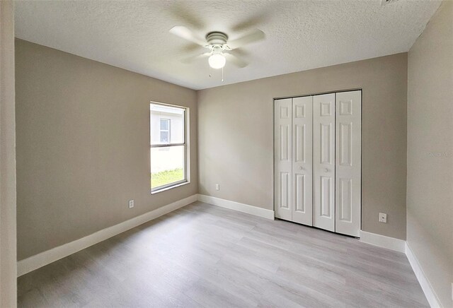 unfurnished bedroom featuring ceiling fan, light hardwood / wood-style floors, a textured ceiling, and a closet