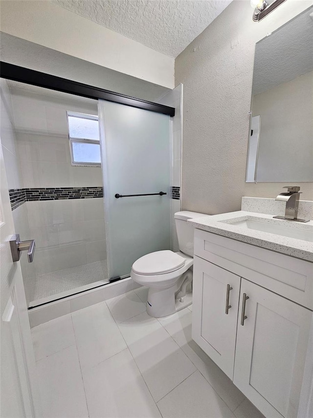 bathroom featuring tile patterned flooring, a textured ceiling, toilet, a shower with door, and vanity