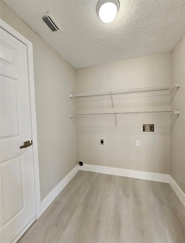 washroom with washer hookup, light wood-type flooring, a textured ceiling, and electric dryer hookup