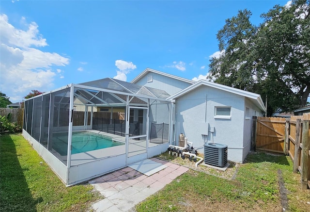 back of property with a patio, a lanai, cooling unit, a yard, and a fenced in pool