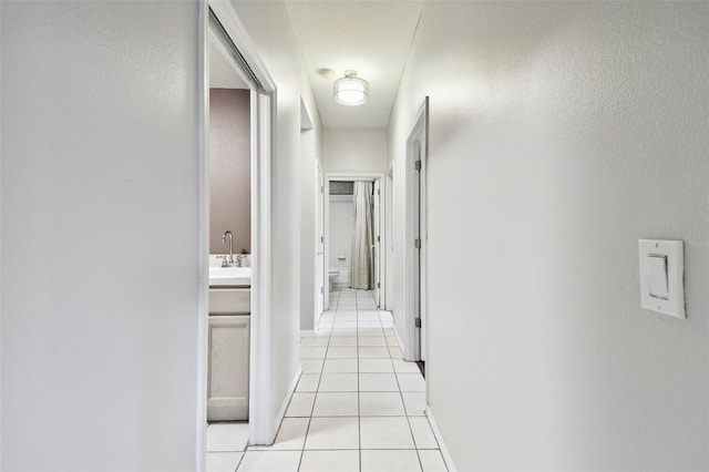 hall featuring light tile patterned flooring and sink