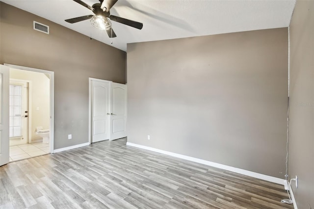 unfurnished bedroom with ceiling fan, a textured ceiling, light hardwood / wood-style flooring, high vaulted ceiling, and ensuite bath