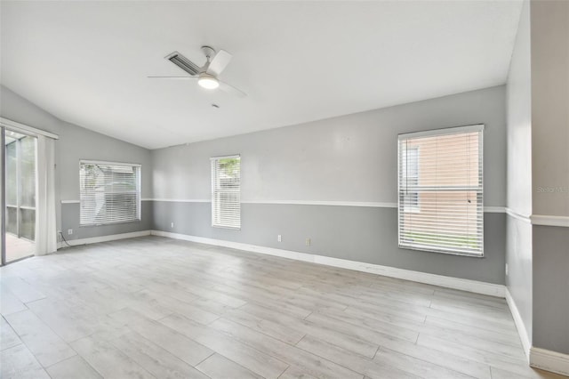 empty room with a wealth of natural light, light hardwood / wood-style floors, ceiling fan, and vaulted ceiling