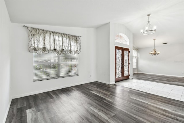 foyer with french doors, hardwood / wood-style flooring, lofted ceiling, and a chandelier