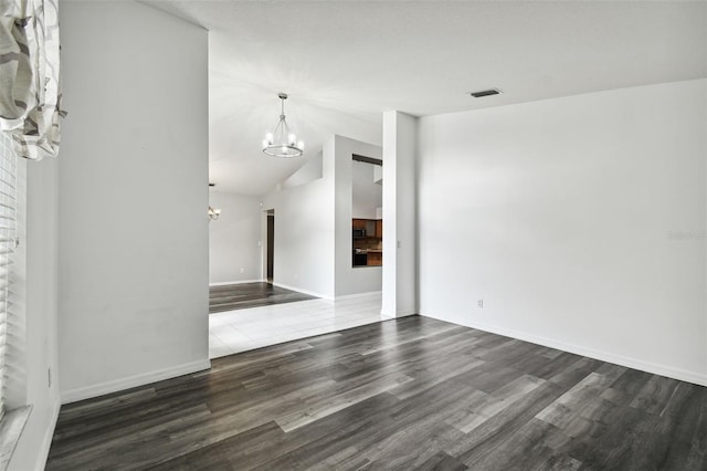 unfurnished living room featuring lofted ceiling, dark wood-type flooring, and a notable chandelier