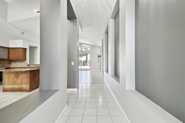 hallway featuring lofted ceiling and light tile patterned flooring